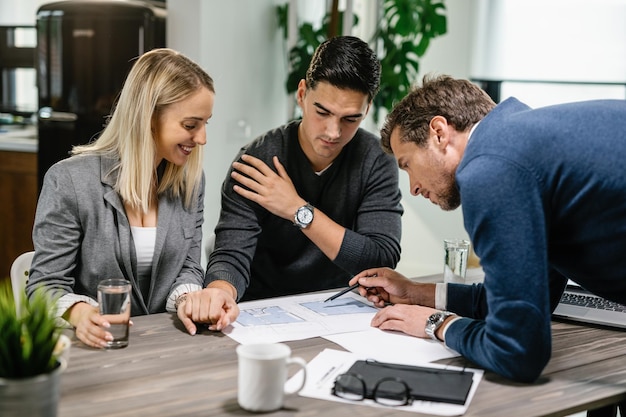 Foto gratuita agente inmobiliario y pareja joven revisando su plan de vivienda en una reunión