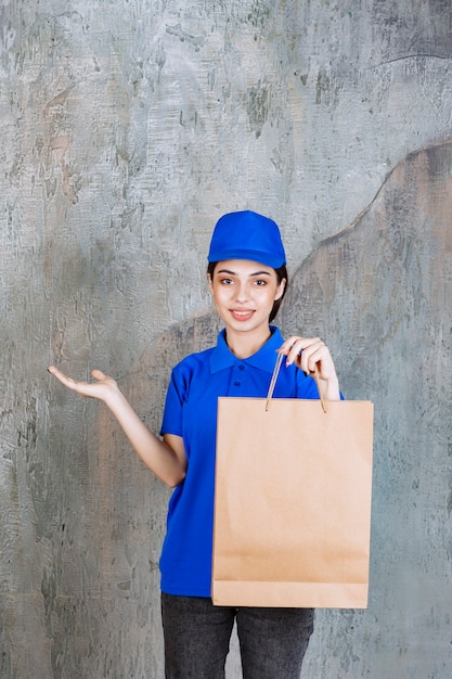 Agente de servicio femenino en uniforme azul sosteniendo una bolsa de cartón.