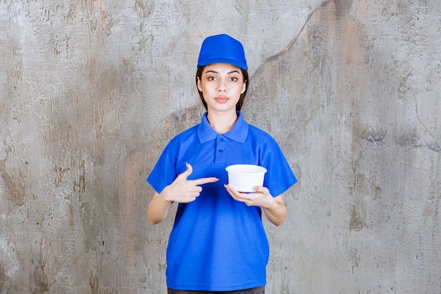 Foto gratuita agente de servicio femenino en uniforme azul sosteniendo un recipiente de plástico