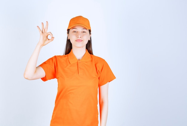 Agente de servicio femenino con uniforme de color naranja y mostrando un signo de mano positivo.
