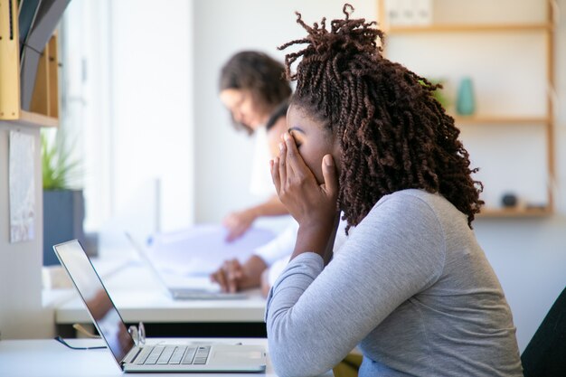 Agotado afroamericano mujer frotando la cara