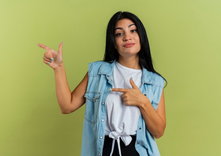 Foto gratuito agradable joven caucásica apunta al lado con las dos manos aisladas sobre fondo verde oliva con espacio de copia