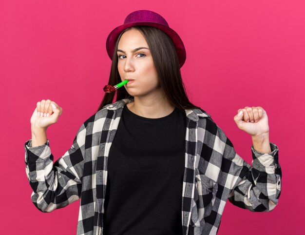 Agradable joven hermosa mujer vistiendo gorro de fiesta soplando silbato de fiesta mostrando sí gesto aislado en la pared rosa