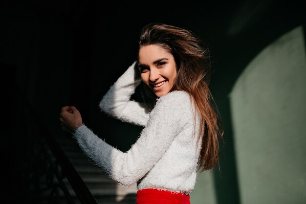 Agradable mujer de pelo castaño que expresa emociones positivas en el espacio oscuro