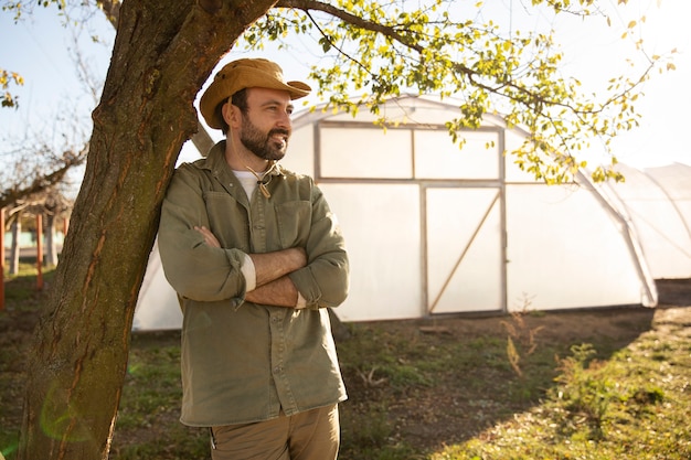 Agricultor posando junto a su invernadero en la granja