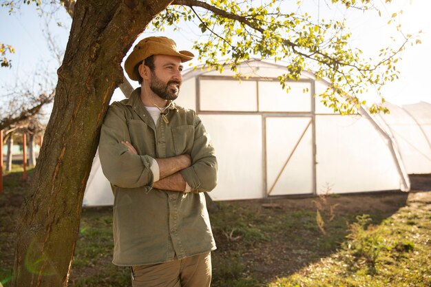 Agricultor posando junto a su invernadero en la granja