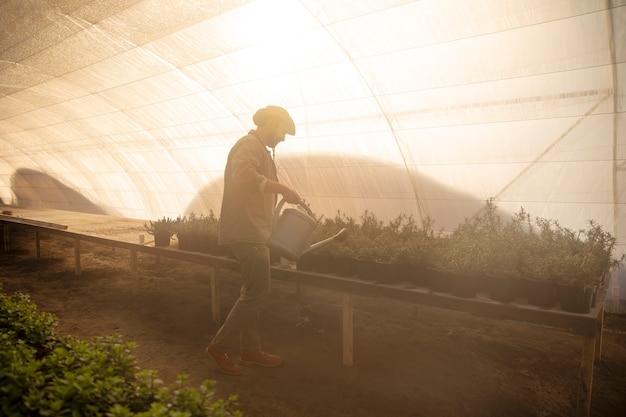 Agricultor regar los cultivos de plantas en su granja