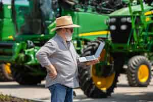 Foto gratuita un agricultor con tractos y laptop