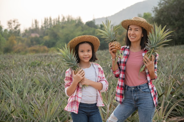 La agricultora asiática ve el crecimiento de la piña en la granja, el concepto de industria agrícola.