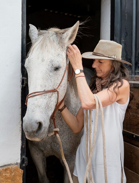 La agricultora de edad avanzada con su caballo en el rancho