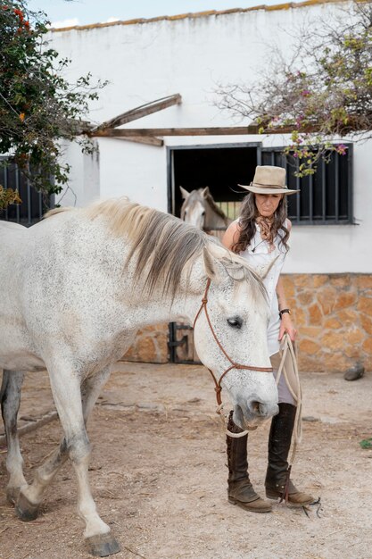 La agricultora de edad avanzada con su caballo en el rancho