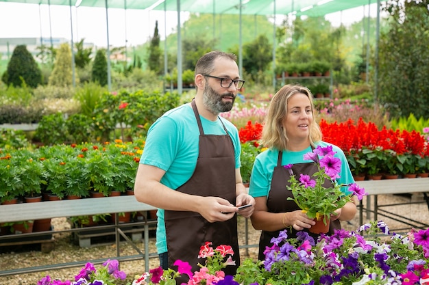 Foto gratuita agricultores caucásicos de pie en invernadero y mirando a otro lado