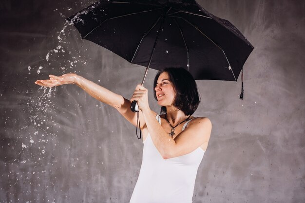 Agua cae sobre mujer bajo paraguas negro