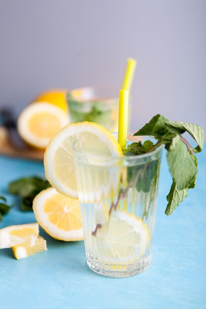 Agua de desintoxicación fresca casera con limones sobre fondo gris y sentado en el escritorio vintage azul