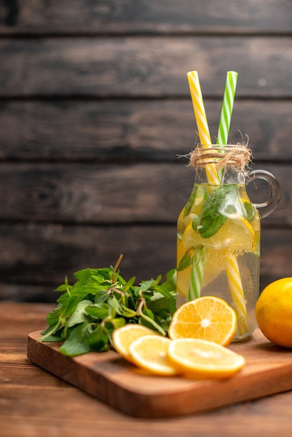 Agua de desintoxicación fresca natural servida con tubo de menta y naranja sobre un fondo marrón