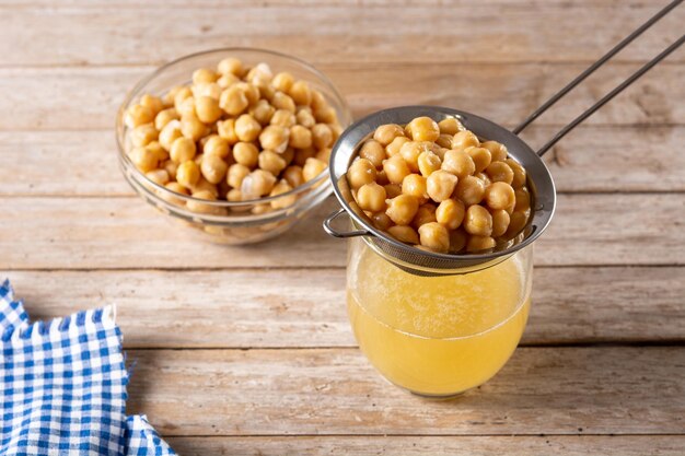 Agua de garbanzo aquafaba sobre mesa de madera El agua de garbanzo es un sustituto de los huevos en los pasteles