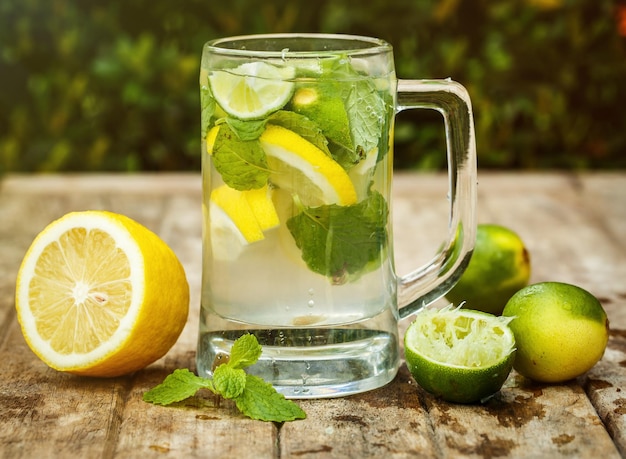 Agua con lima limón y menta sobre una tabla de madera