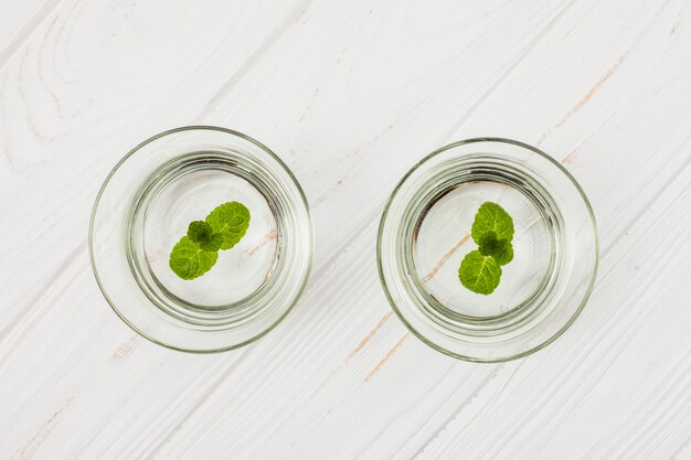 Agua con menta en vasos sobre mesa blanca