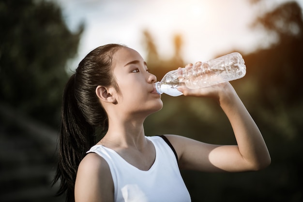 Agua potable hermosa joven de la mujer de la aptitud después de correr ejercicio