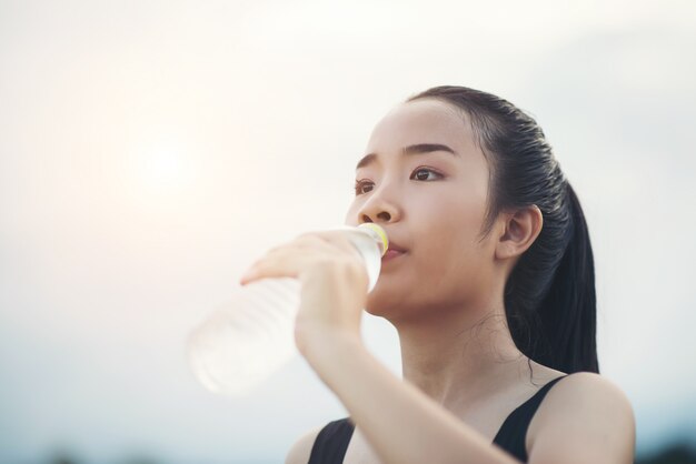 Agua potable hermosa joven de la mujer de la aptitud después de correr ejercicio