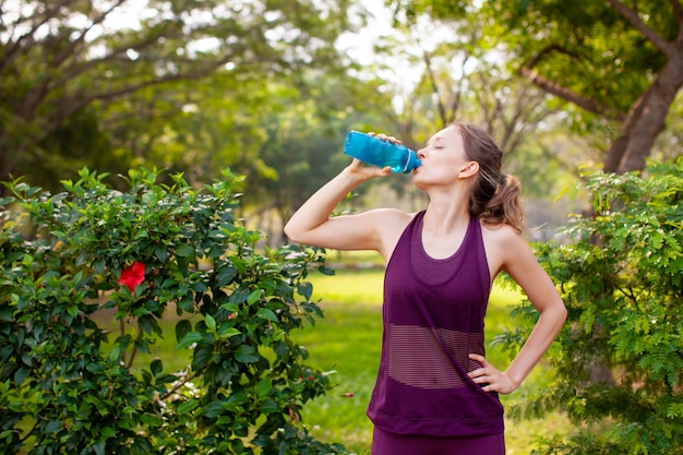 Agua potable de la mujer deportiva en parque