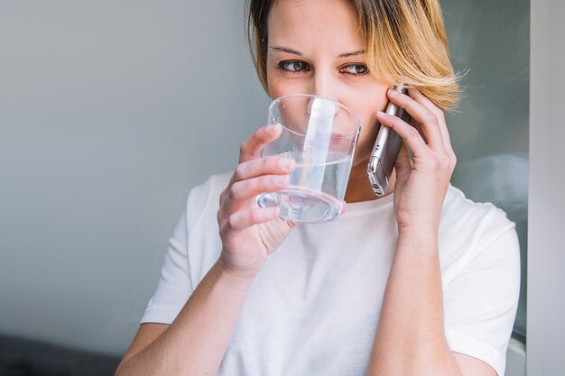 Agua potable de mujer y hablando por teléfono