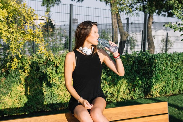 Agua potable de la mujer hermosa en parque