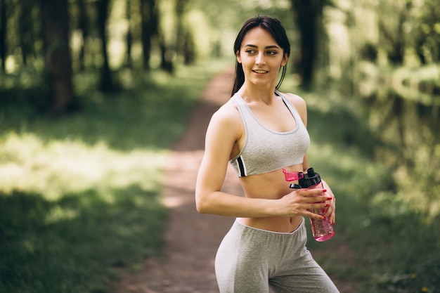 Agua potable de niña deportiva en el parque