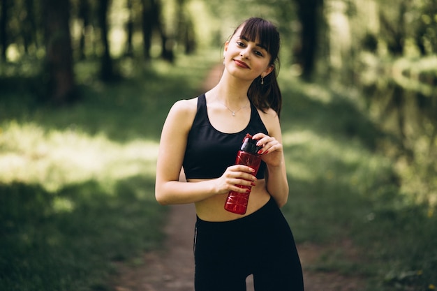 Agua potable de niña deportiva en el parque