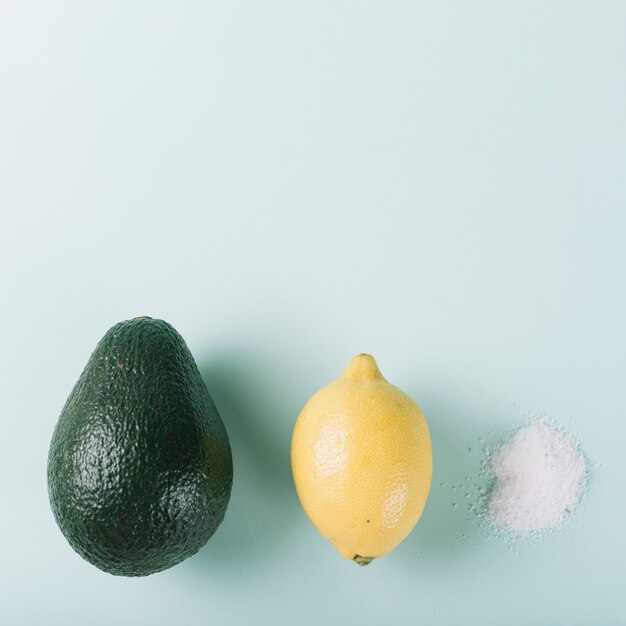 Aguacate limón y sal dispuestas en una fila sobre fondo verde