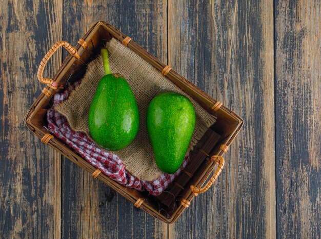 Aguacates en una cesta en una mesa de madera. aplanada