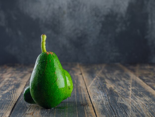 Aguacates en madera y pared de yeso. vista lateral.