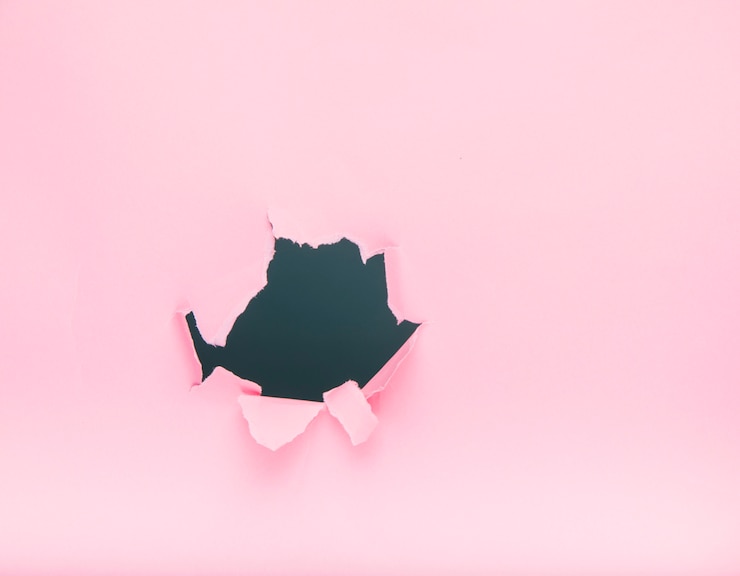Foto gratuito agujero en papel rosa