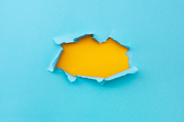 Foto gratuita agujero rasgado en color azul y rasgado de papel con fondo amarillo. textura de papel rasgado con área de espacio de copia de texto