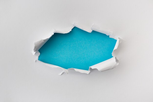 Agujero rasgado en color blanco y rasgado de papel con fondo azul. Textura de papel rasgado con área de espacio de copia de texto
