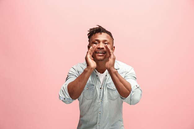 Aislado en rosa joven afroamericano gritando en el estudio