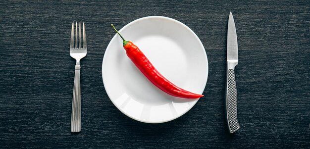 Ajíes planos sobre un plato blanco y cubiertos sobre un fondo negro