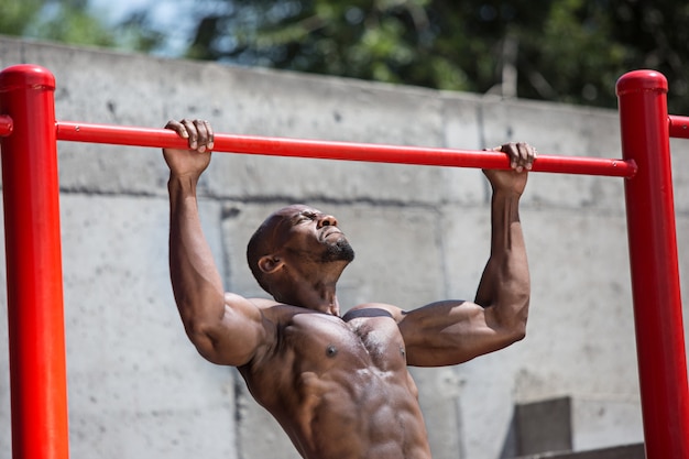 Foto gratuita ajuste atleta haciendo ejercicios en el estadio. hombre afro al aire libre en la ciudad.