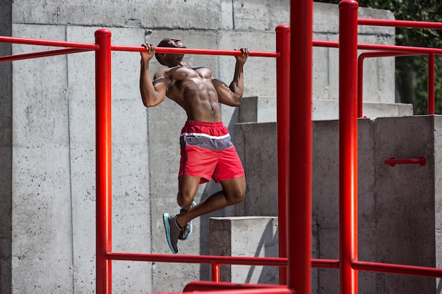 Foto gratuita ajuste atleta haciendo ejercicios en el estadio. hombre afroamericano o afroamericano al aire libre en la ciudad