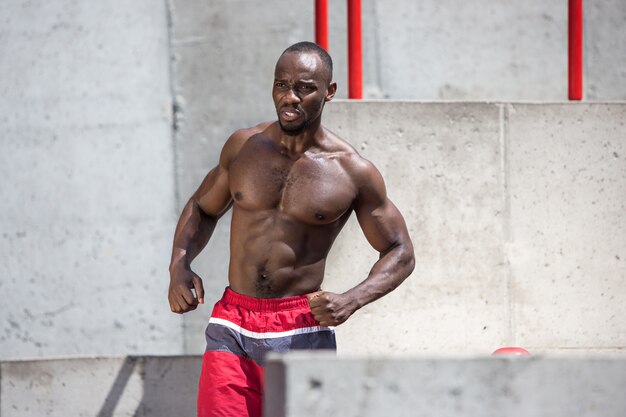 ajuste atleta haciendo ejercicios en el estadio. Hombre afroamericano o afroamericano al aire libre en la ciudad