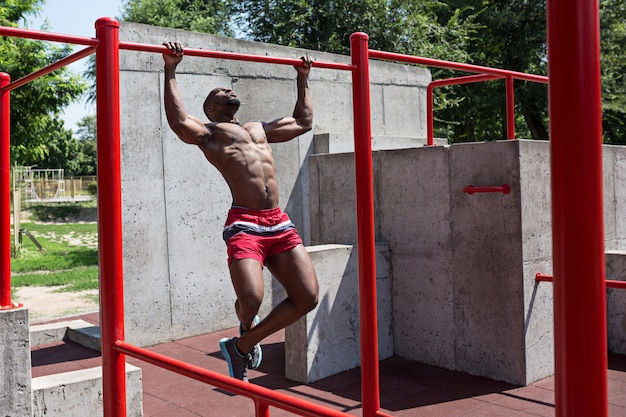 ajuste atleta haciendo ejercicios en el estadio. Hombre afroamericano o afroamericano al aire libre en la ciudad