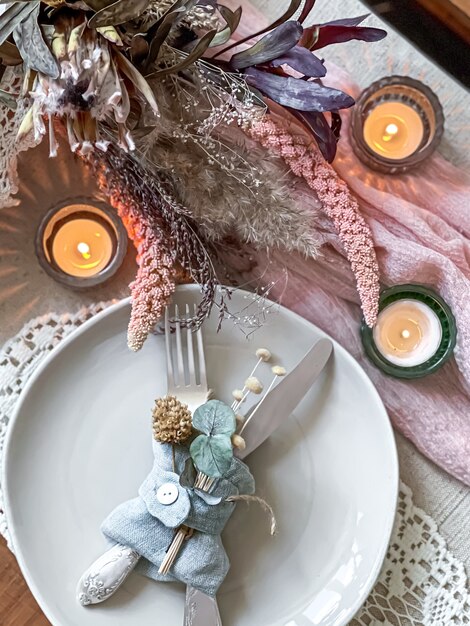 Ajuste de la mesa para una cena romántica, boda o cualquier ocasión con velas y flores secas como decoración.