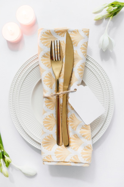 Ajuste de la mesa de comedor con la servilleta y las velas dobladas en el fondo blanco