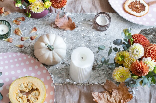 Ajuste de la tabla festiva con velas de calabazas y flores de crisantemo