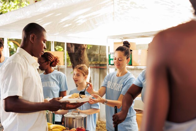 Al aire libre, un equipo diverso de voluntarios distribuye comida gratuita a los necesitados, incluidos refugiados y personas sin hogar. Su servicio compasivo brinda apoyo vital a los desfavorecidos.