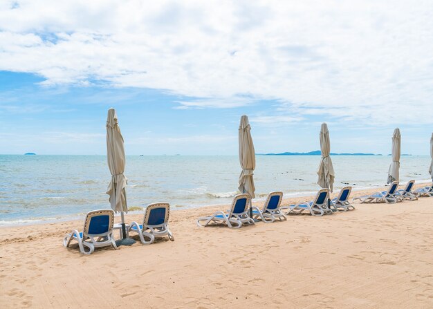 Al aire libre con paraguas y silla en la hermosa playa tropical y el mar