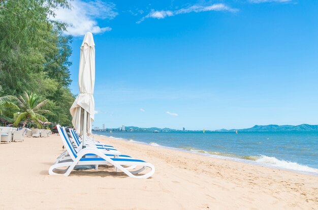 Al aire libre con paraguas y silla en la hermosa playa tropical y el mar