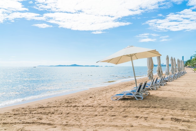 Al aire libre con paraguas y silla en la hermosa playa tropical y el mar