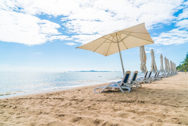 Al aire libre con paraguas y silla en la hermosa playa tropical y el mar