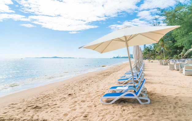 Al aire libre con paraguas y silla en la hermosa playa tropical y el mar